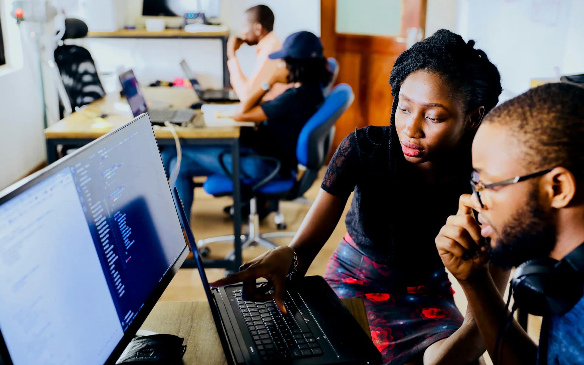 Équipe de développeurs africains travaillant ensemble devant des écrans de code